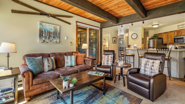 A living room with a brown leather sofa, a leather recliner, a wooden coffee table, and a painting on the wall. - 2BR Mountain Condo | Walk to Resort, Hot Tubs, Pool (Steamboat Springs)