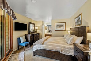 A bedroom with a bed, dresser, chair, and a television. - 2BR Mountain Condo | Walk to Resort, Hot Tubs, Pool (Steamboat Springs)