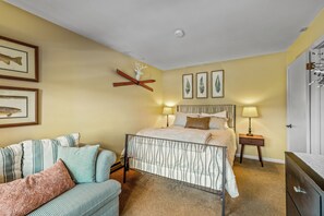A bedroom with a bed, a nightstand, a chair, and wall art. - Mountain Days and Hot Tub Nights | Private Balcony (Steamboat Springs)