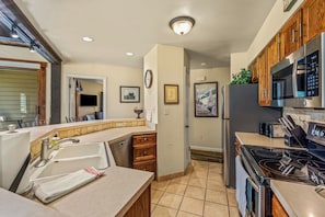 A modern kitchen with a built-in dishwasher, stainless steel appliances, wooden cabinets, and a tiled backsplash. - Mountain Days and Hot Tub Nights | Private Balcony (Steamboat Springs)