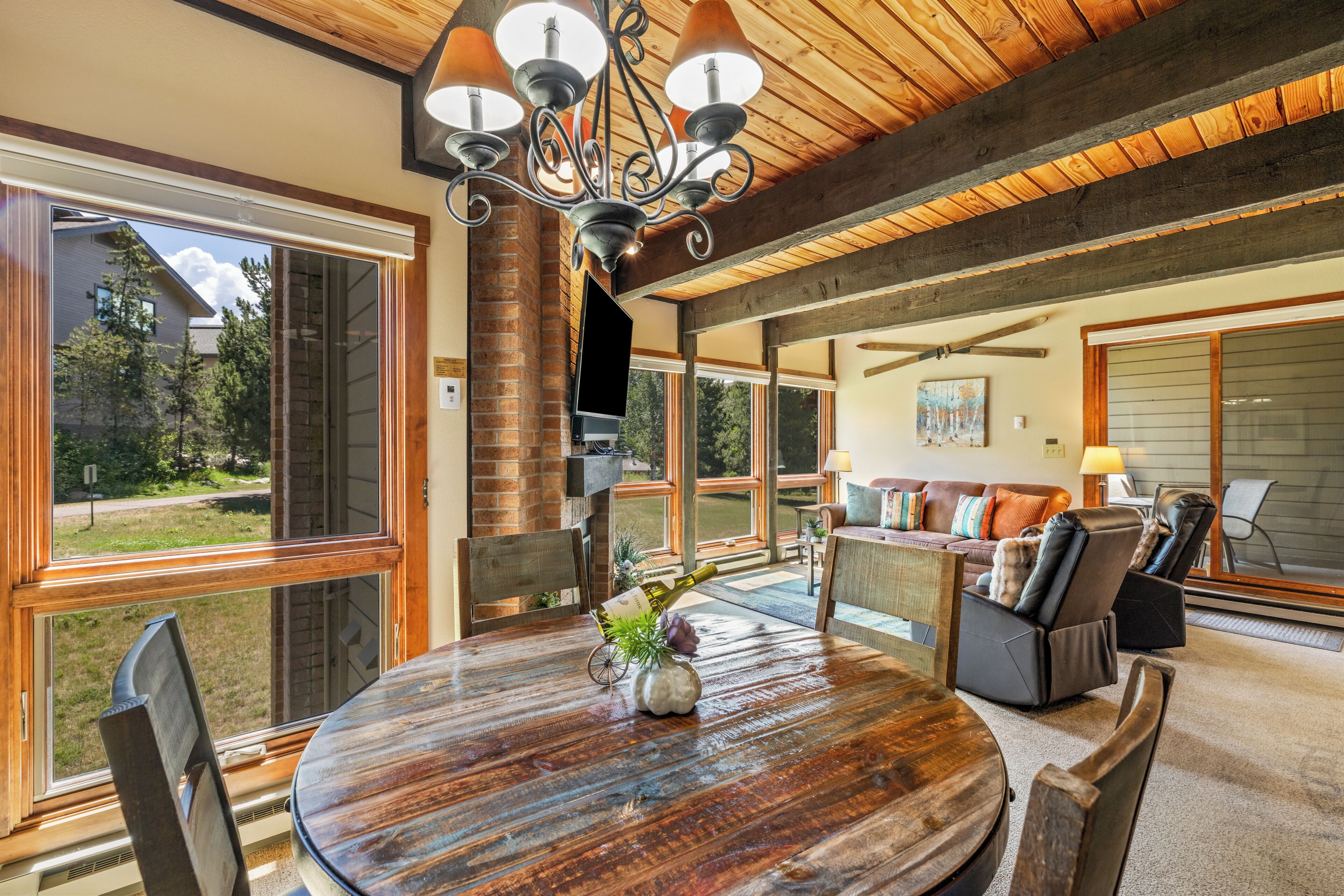 A spacious living area with a large round table, comfortable seating, and a view of the outdoors.