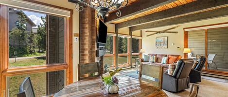 A spacious living area with a large round table, comfortable seating, and a view of the outdoors.