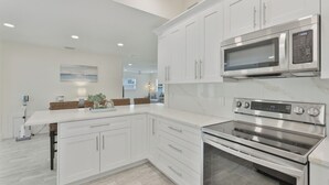 Una cocina moderna con armarios blancos, microondas integrado y horno de acero inoxidable.