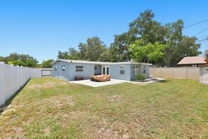 Einbungalow mit überdachter Terrasse, umzäunter Garten und Garage.