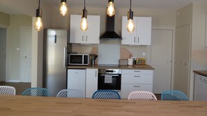 Una cocina moderna con armarios blancos, microondas, tostadora y una mesa de comedor de madera con sillas.