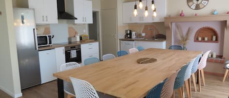 Una cocina moderna con armarios blancos, una mesa de comedor de madera y sillas azules.