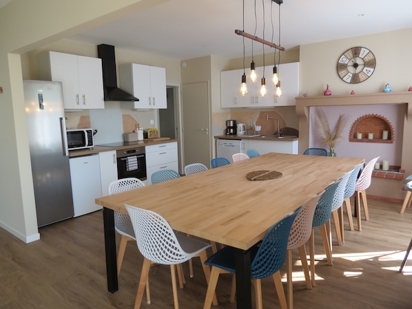 Een moderne keuken met witte kasten, een houten eettafel en blauwe stoelen.