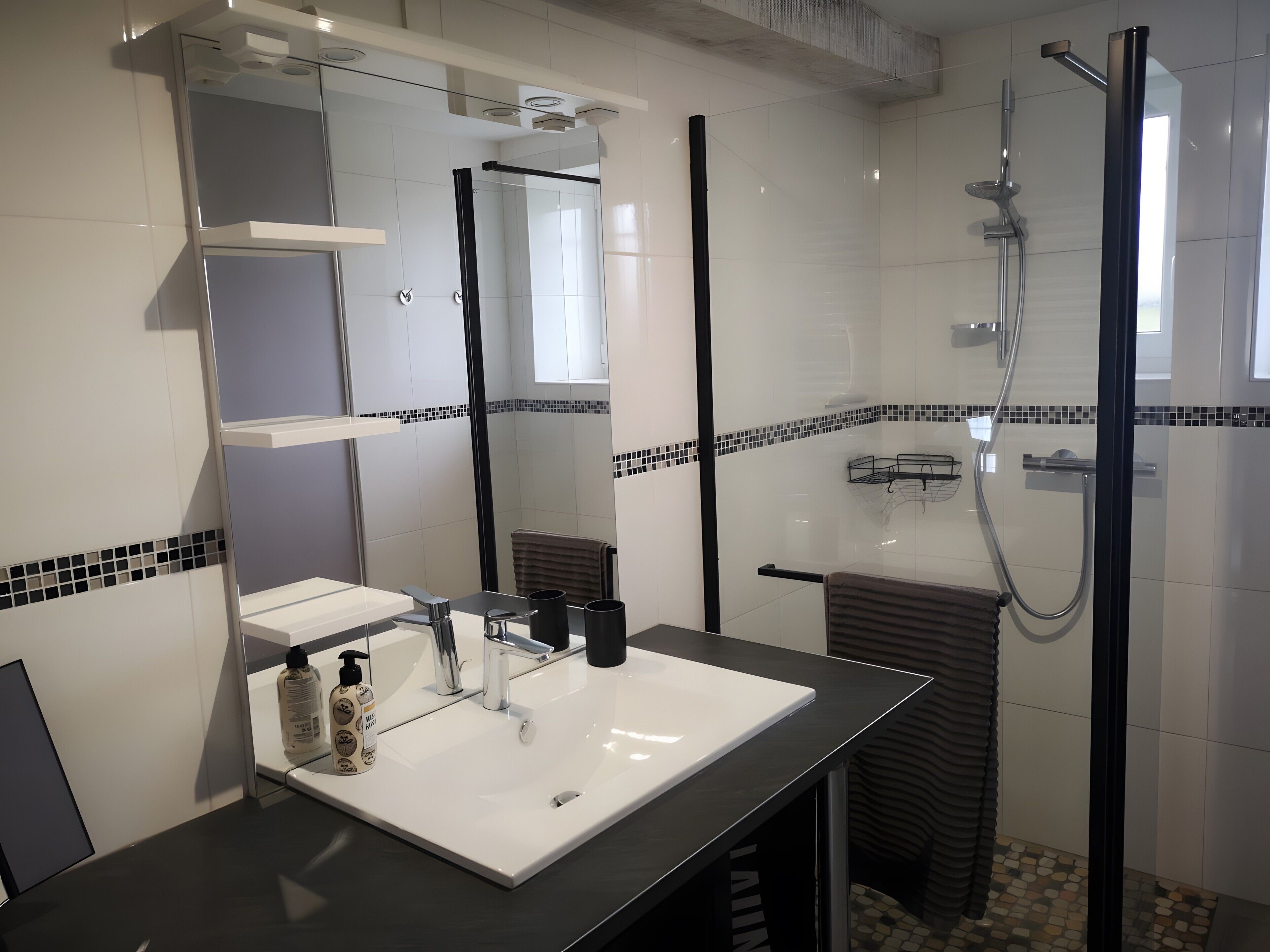 A modern bathroom with a white sink, a mirror, a shower, and a tiled floor.