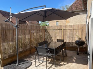 A patio with a table and chairs, a barbecue grill, and a large umbrella.