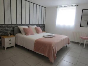 A bedroom with a bed, a nightstand, a chair, a radiator, and a window with curtains.