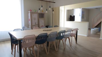 Un coin repas avec une table et des chaises en bois, un meuble contenant des objets décoratifs et un escalier en arrière-plan.