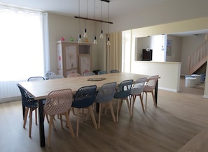 A dining area with a wooden table and chairs, a cabinet with decorative items, and a staircase in the background.
