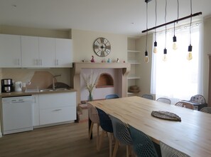Una cocina moderna con armarios blancos, una mesa de comedor de madera y una chimenea de ladrillo.