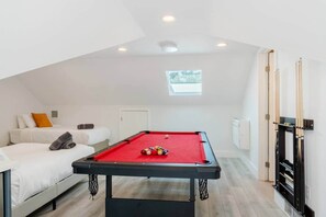 Une pièce avec une table de billard, un lit, une fenêtre et une cheminée.