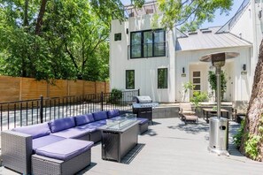 An outdoor patio with a sofa, grill, and dining area.
