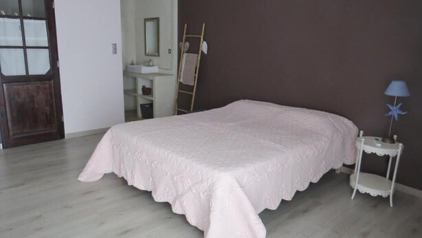 A bedroom with a bed, a small bedside table, a mirror, and a door.