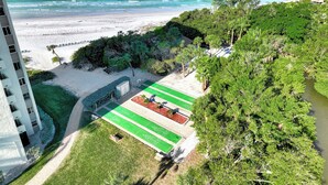 En strandutsikt med en tennisbana och en byggnad.