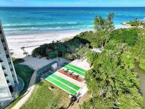 A beach view with a tennis court and a building. - Remodeled Siesta Key Villa – Steps to Private Beach & Village! (Sarasota)