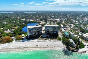 An aerial view of a coastal area with a beach, two modern buildings, and a lake in the background. - Remodeled Siesta Key Villa – Steps to Private Beach & Village! (Sarasota)