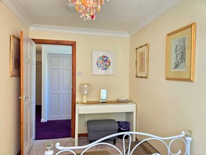 A bedroom with a bed, a desk, a chair, a lamp, and a chandelier. - Unique and character-filled cottage - Pass the Keys (Brynteg)