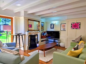 A living room with a fireplace, a television, and a green sofa. - Unique and character-filled cottage - Pass the Keys (Brynteg)