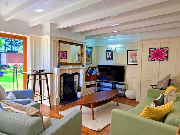 Una sala de estar con chimenea, televisor y sofá verde.