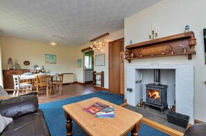 A living room with a fireplace, a dining area, and a kitchen. - Peaceful Property North of the island - Pass the Keys (Amlwch)