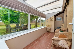 A sunlit room with a large window, a patio area with chairs, and a small table. - Peaceful Property North of the island - Pass the Keys (Amlwch)