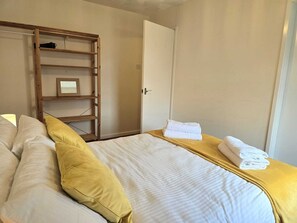 Une chambre à coucher avec un lit, une étagère en bois, une porte et une pile de serviettes.