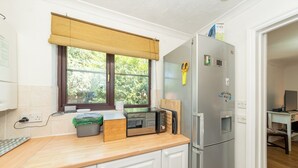 A compact kitchen with a microwave, toaster, and refrigerator, a window with a view of greenery, and a small dining area. - Quiet Green&Peaceful Home Near Reading University - Pass the Keys (Reading)