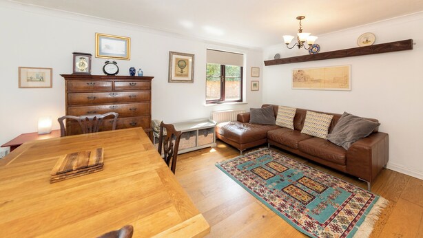 A living room with a wooden dining table, a brown leather sofa, and a patterned rug. - Quiet Green&Peaceful Home Near Reading University - Pass the Keys (Reading)