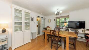 A dining area with a wooden table and chairs, a television, and a cabinet with glass doors.