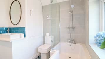 Un baño moderno con bañera, cabina de ducha con mampara de vidrio, inodoro y lavabo.
