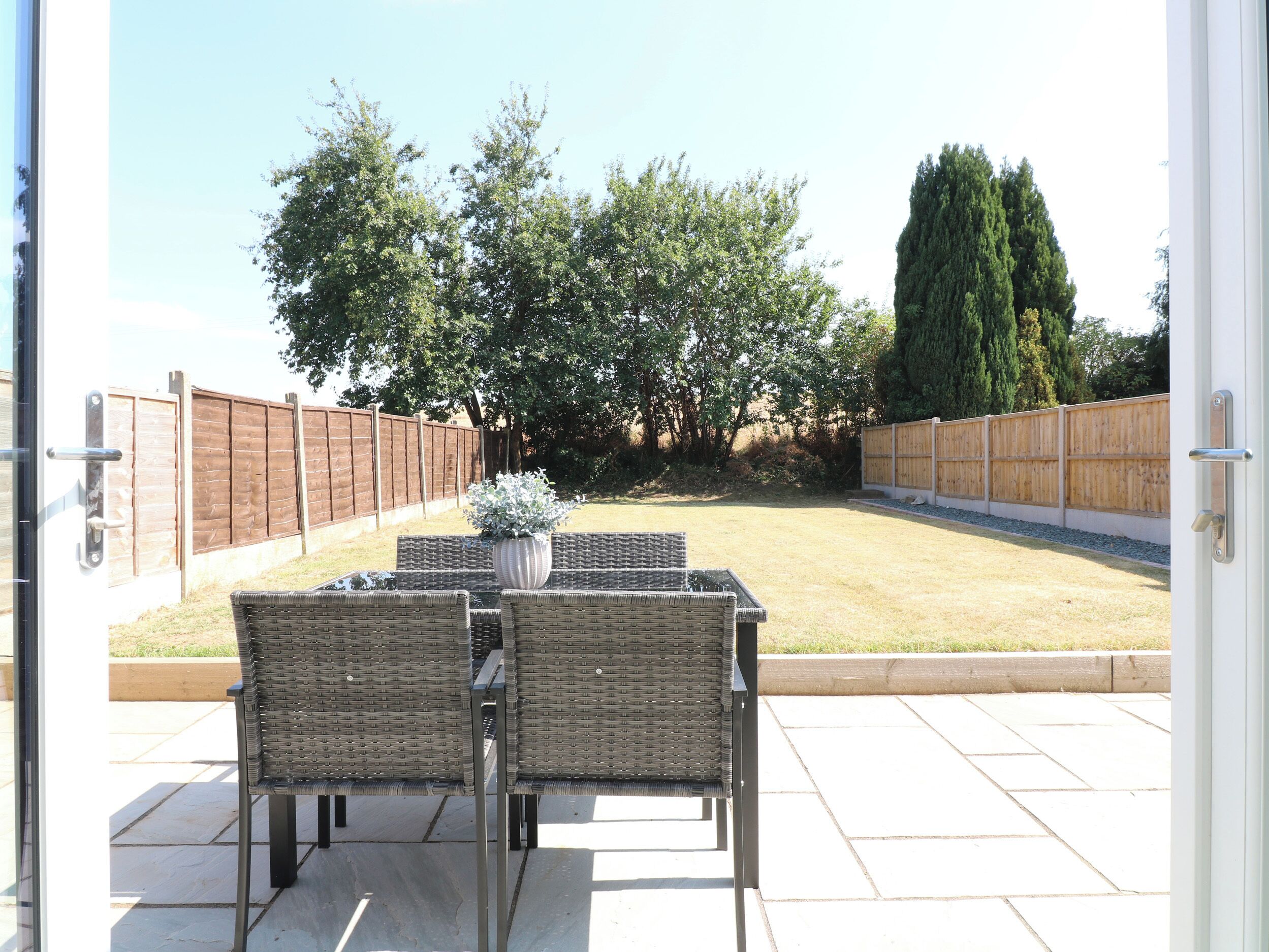 An outdoor patio with wicker furniture and a potted plant.