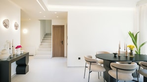 Uma sala de jantar moderna com uma mesa redonda, cadeiras e uma escada que leva a outro espaço.