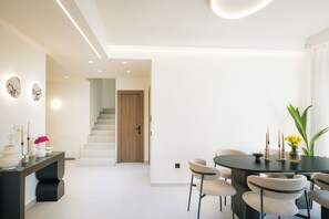 Ein moderner Essbereich mit einem runden Tisch, Stühlen und einer Treppe, die in einen anderen Raum führt.