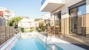 Um edifício moderno com piscina, guarda-corpos de vidro e vista para o bairro.