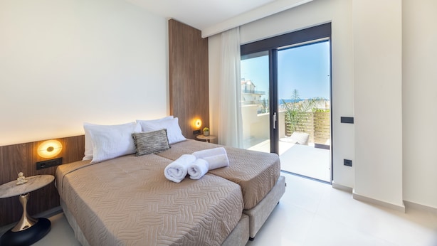 Quarto moderno com uma cama grande, abajures e vista para o exterior através de uma porta de vidro deslizante.