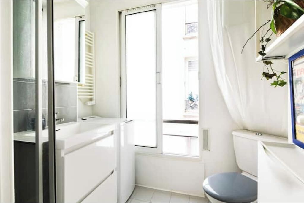 A small, bright bathroom with a toilet, sink, and window.