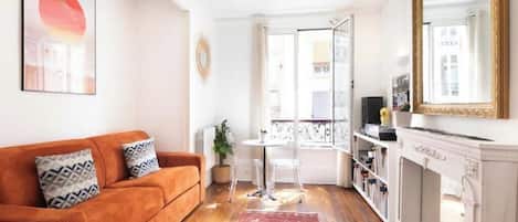 A living room with a sofa, a small table, a fireplace, and a balcony with a view.