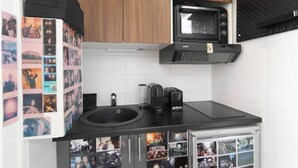 A kitchen with a black countertop, a coffee maker, a microwave, and a sink. - Cosy apartment in Sacré Cœur - 1BDR (Paris)