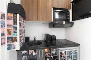 Eine Küche mit schwarzer Arbeitsplatte, einer Kaffeemaschine, einer Mikrowelle und einem Spülbecken.