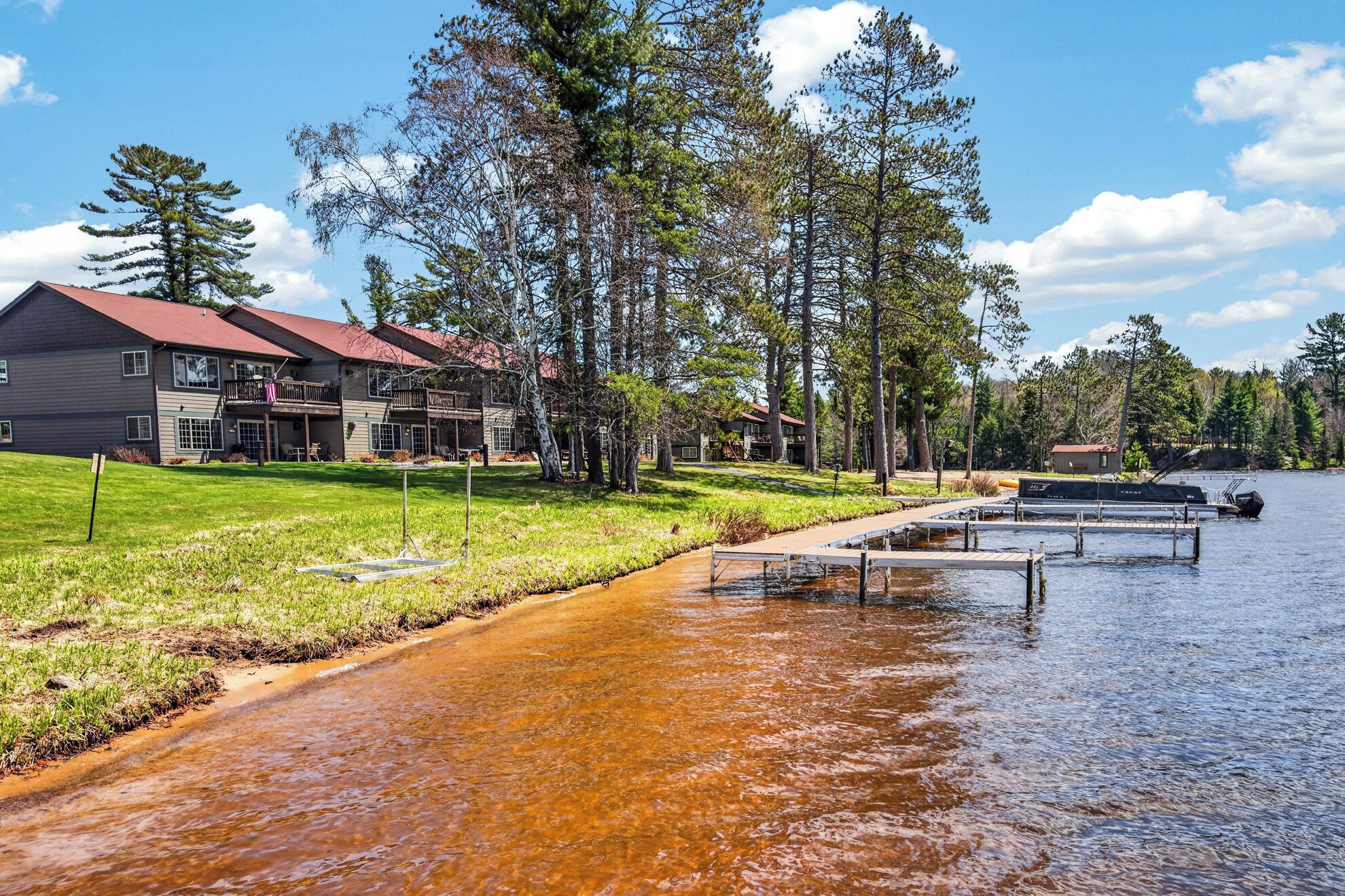 A lakeside property with a house, dock, and docked boat.