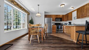 Uma cozinha moderna com armários de madeira, eletrodomésticos de aço inoxidável e uma janela grande com vista para uma floresta.