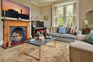 A living room with a fireplace, a piano, a sofa, and a coffee table.