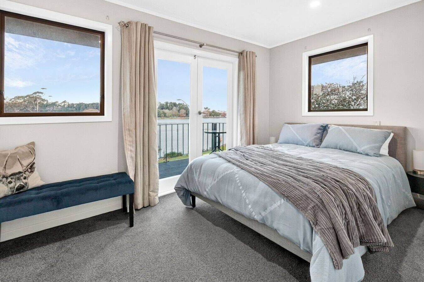 Une chambre à coucher comprenant un lit, un banc, une fenêtre donnant sur un paysage agréable et une porte menant à un balcon.