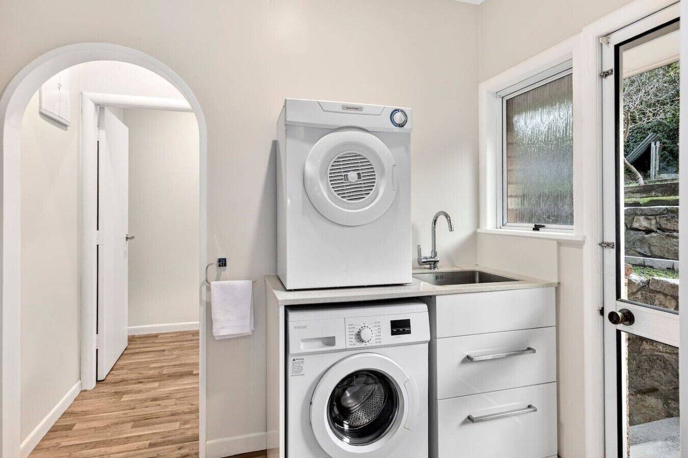 A compact laundry area with a washing machine, dryer, and sink.