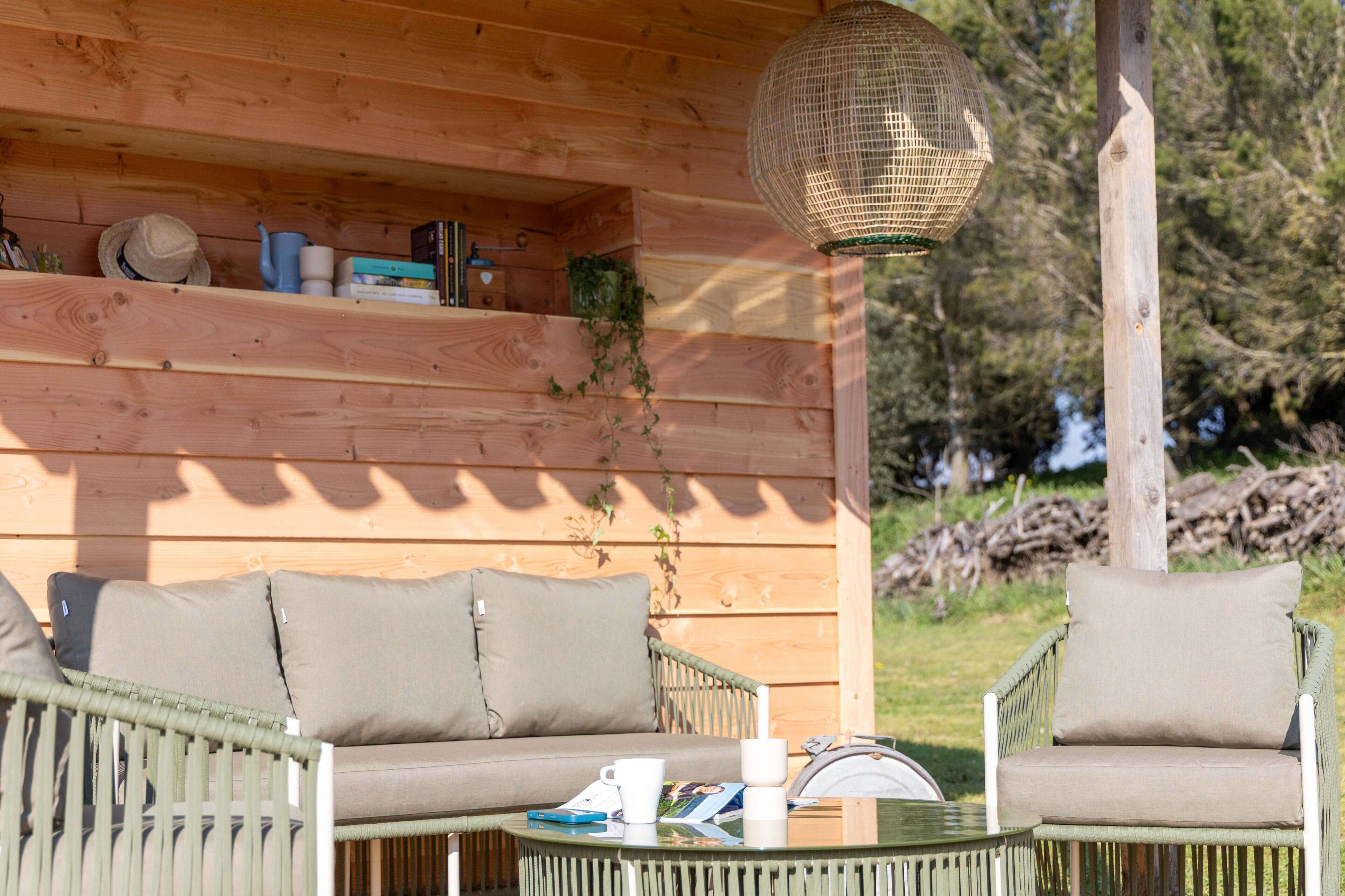 Una baita in legno con un divano, poltrone, un tavolo e un lampadario.
