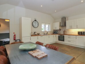 A modern kitchen with white cabinets, a stainless steel range hood, and a built-in oven. - Glen Lochay Lodge (Killin)