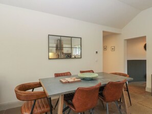 A dining area with a rectangular table, six brown chairs, and a decorative green object on the table. - Glen Lochay Lodge (Killin)